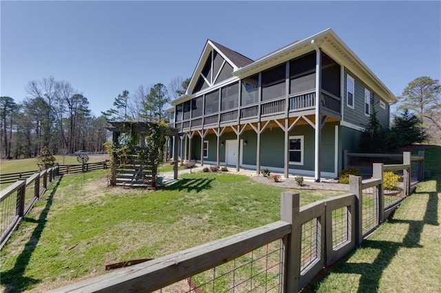 rear view of property featuring a yard, fence, and a sunroom