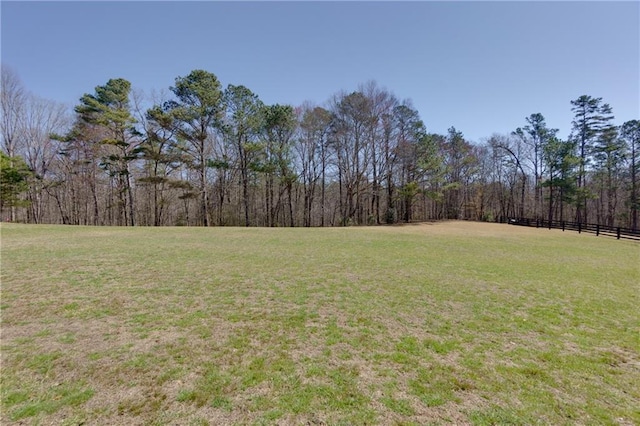 view of yard featuring a forest view and fence