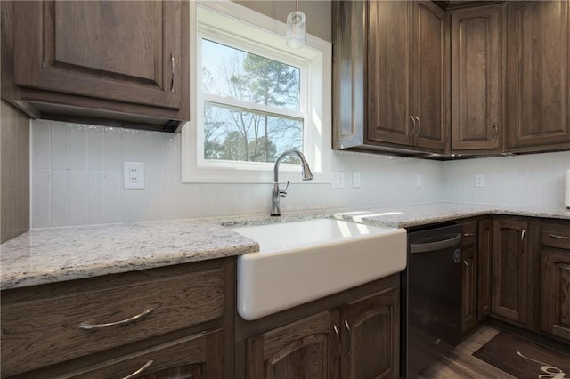 kitchen with a sink, dishwashing machine, and light stone counters