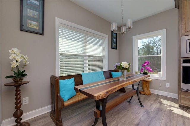 dining area featuring plenty of natural light, light wood-type flooring, and an inviting chandelier