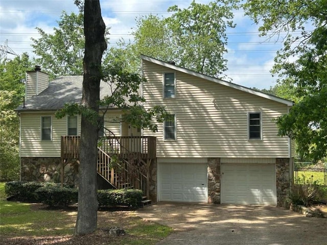 view of property exterior featuring stone siding, an attached garage, driveway, and a chimney