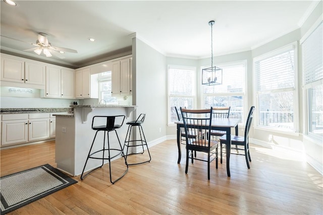 kitchen featuring light hardwood / wood-style floors, light stone countertops, white cabinetry, and a kitchen bar