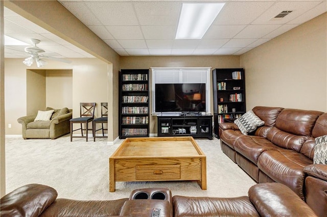 carpeted living room featuring ceiling fan and a paneled ceiling