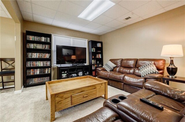 carpeted living room featuring a drop ceiling