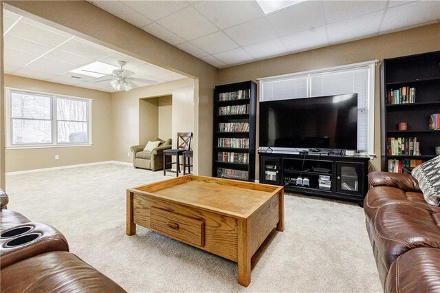 carpeted living room featuring ceiling fan and a drop ceiling