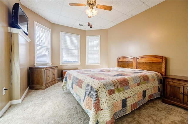 bedroom featuring ceiling fan, light colored carpet, and a paneled ceiling