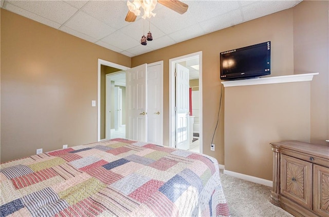 bedroom with ceiling fan, a drop ceiling, light carpet, and ensuite bath