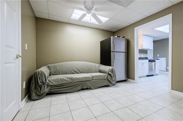 living room with ceiling fan, a drop ceiling, and light tile patterned floors