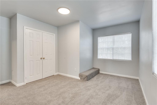 unfurnished bedroom with light colored carpet and a closet