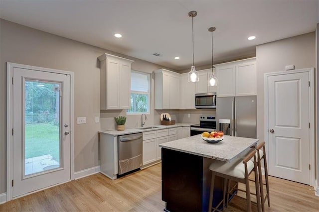 4230 Moore Rd, Conley, GA 30288 - kitchen with stainless steel appliances, light wood-type flooring, white cabinetry, pendant lighting, and a kitchen island