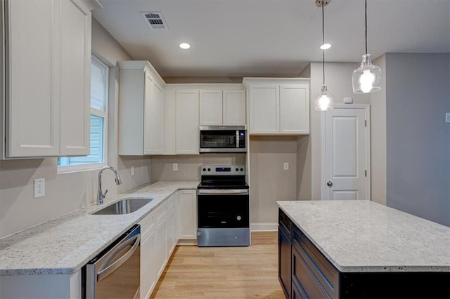 4230 Moore Rd, Conley, GA 30288 - kitchen with stainless steel appliances, light wood-style floors, white cabinets, hanging light fixtures, and a center island