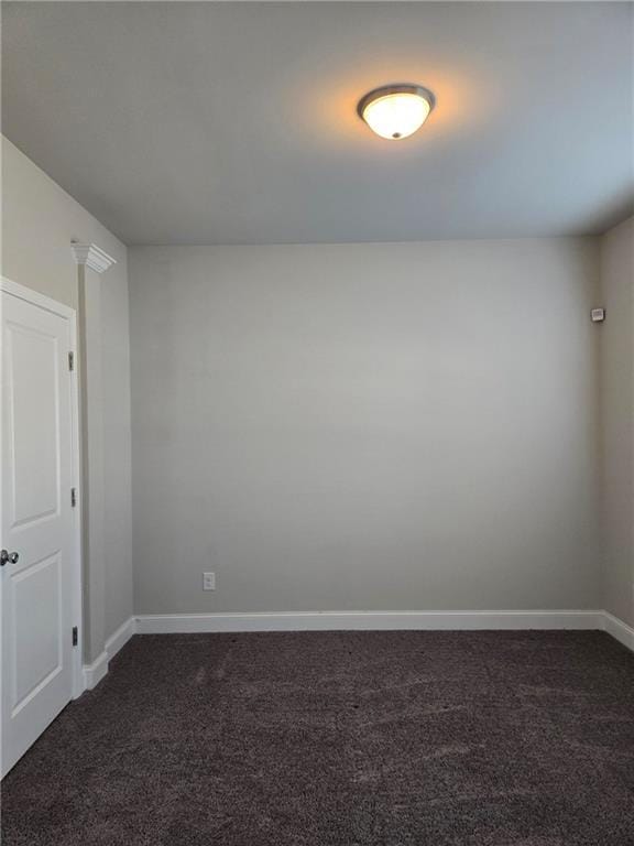 unfurnished room with dark carpet and baseboards