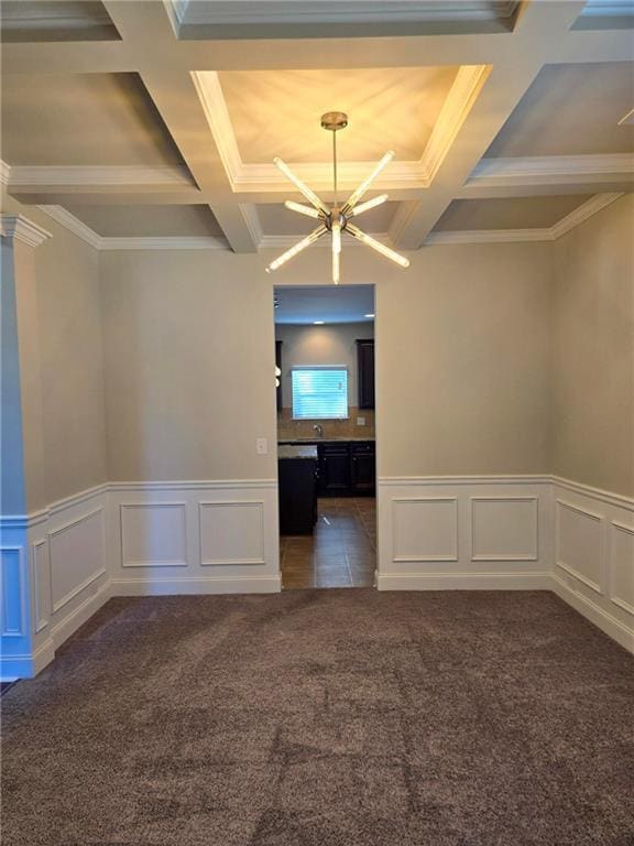 unfurnished room featuring an inviting chandelier, dark colored carpet, beam ceiling, and coffered ceiling