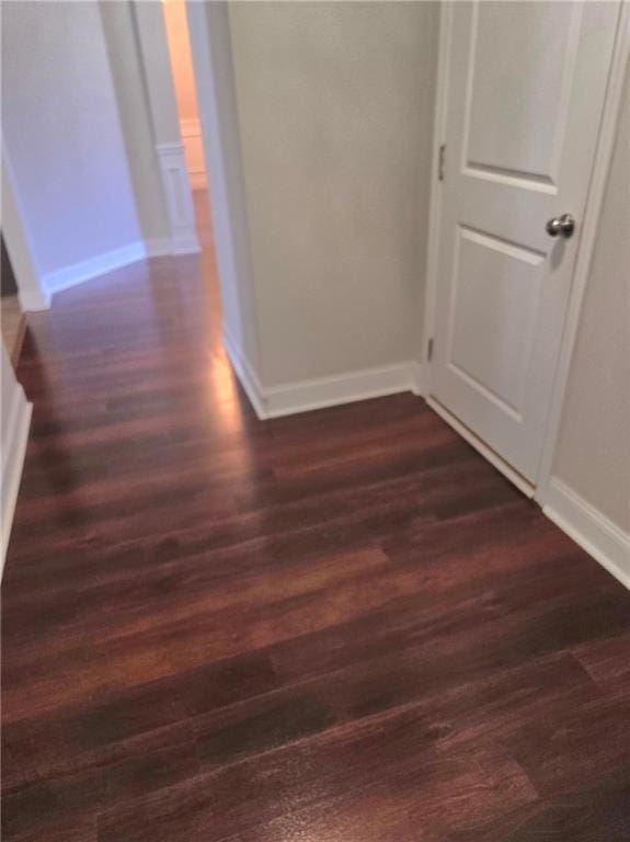 hallway featuring dark wood-style flooring and baseboards