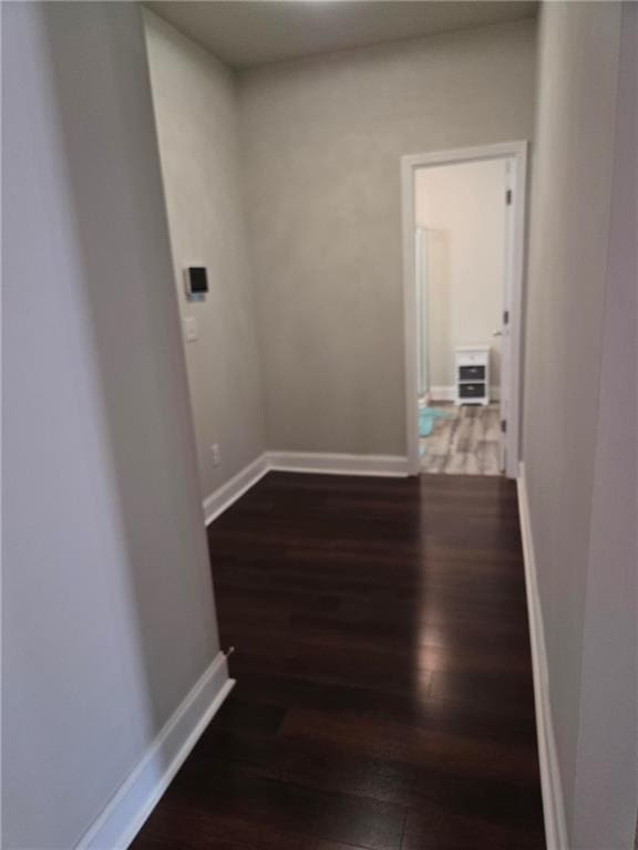 hall with dark wood-style floors, heating unit, and baseboards