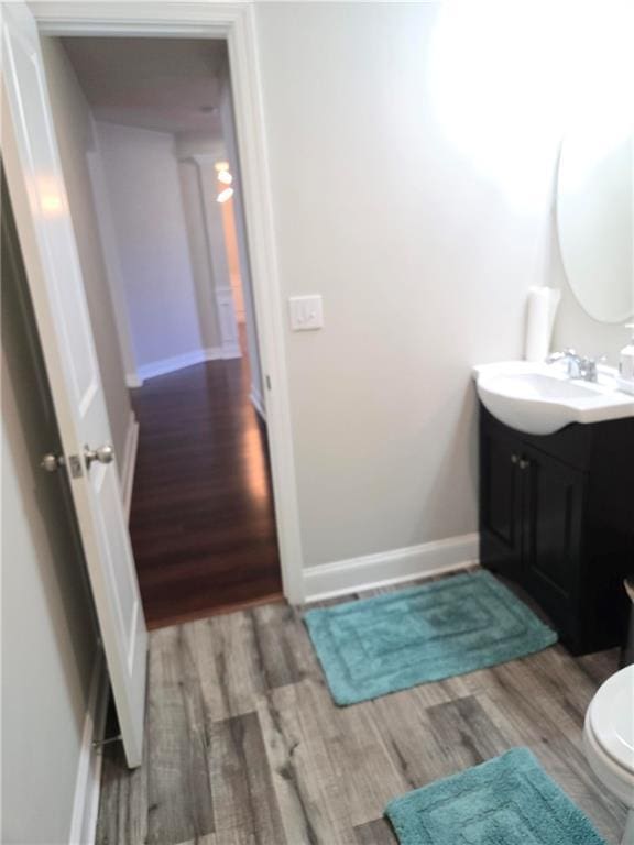 bathroom featuring toilet, vanity, baseboards, and wood finished floors