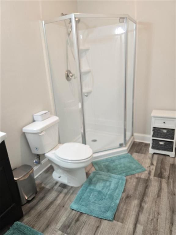 full bathroom featuring baseboards, toilet, wood finished floors, vanity, and a shower stall