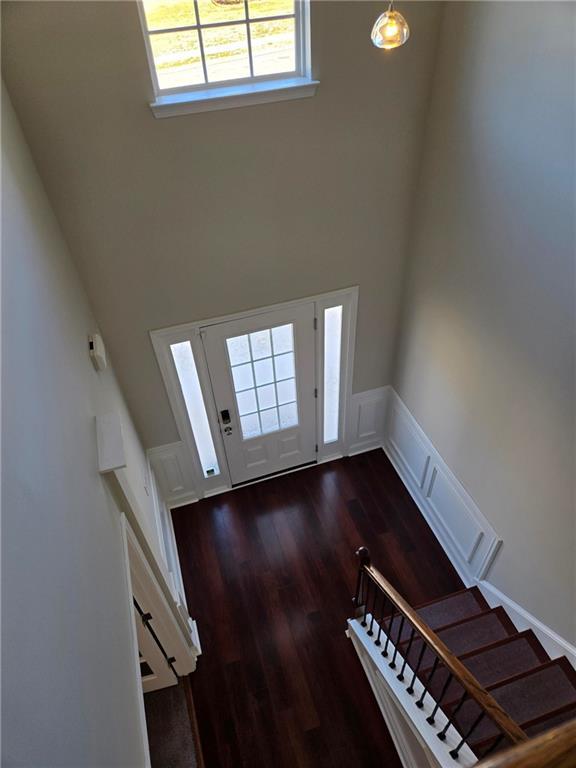 foyer entrance with dark wood-style floors, a wainscoted wall, a decorative wall, and stairway