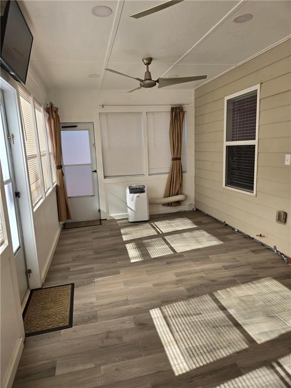 unfurnished sunroom with ceiling fan