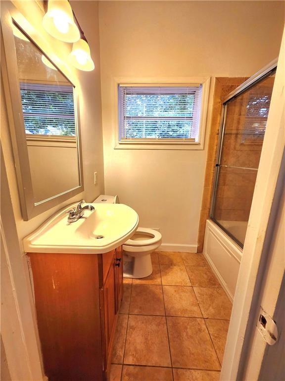 full bathroom with tile patterned flooring, vanity, shower / bath combination with glass door, and toilet