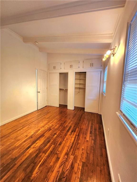 unfurnished bedroom with multiple closets, dark wood-type flooring, and beam ceiling