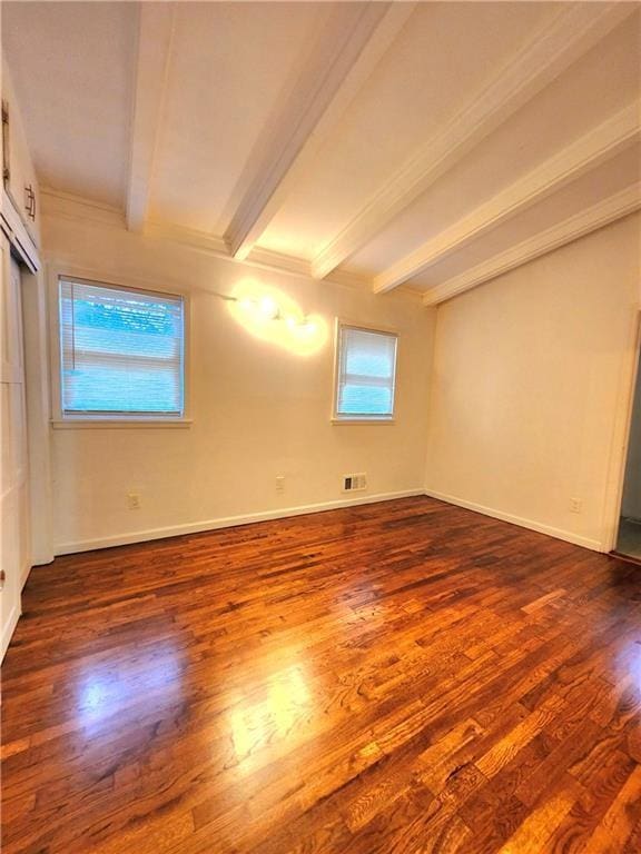 spare room with dark wood-type flooring and beamed ceiling