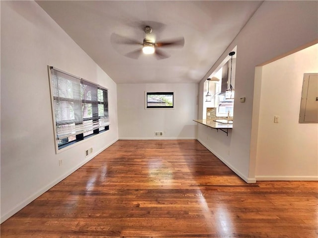 unfurnished living room featuring dark hardwood / wood-style flooring, vaulted ceiling, electric panel, and ceiling fan