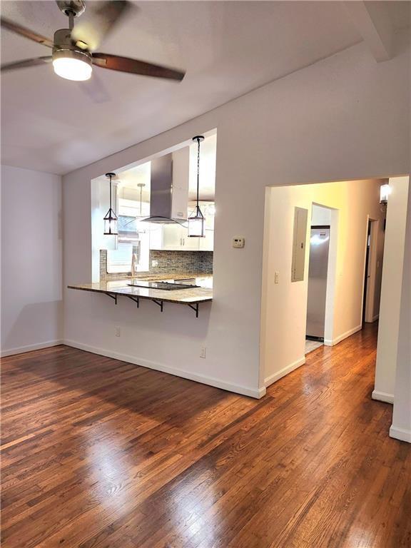 kitchen featuring a breakfast bar area, hanging light fixtures, stainless steel fridge, kitchen peninsula, and island exhaust hood