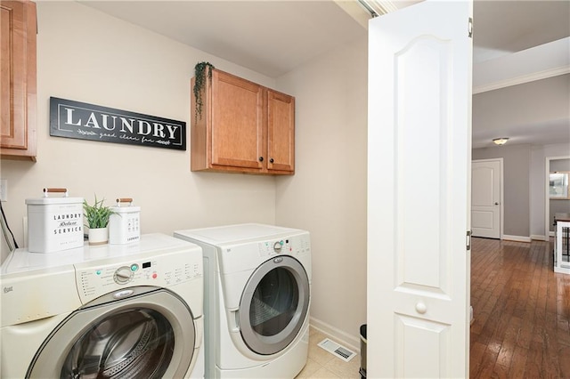 laundry area with cabinet space, washing machine and dryer, baseboards, and wood-type flooring