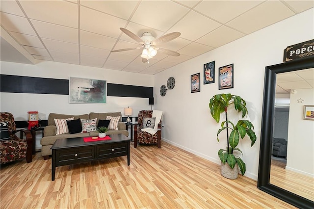 living room with a paneled ceiling, wood finished floors, a ceiling fan, and baseboards
