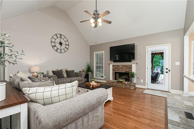 living room with a ceiling fan, high vaulted ceiling, a fireplace, light wood-style flooring, and baseboards