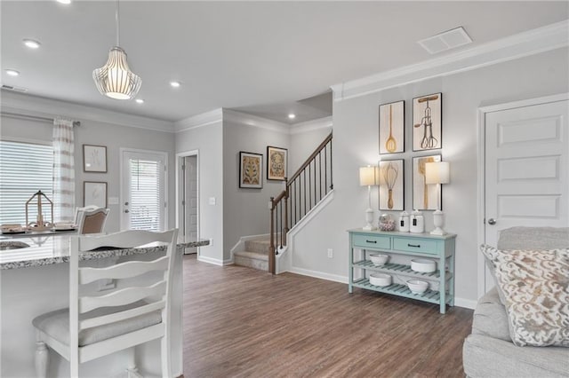 interior space featuring ornamental molding, a kitchen breakfast bar, dark hardwood / wood-style floors, and pendant lighting