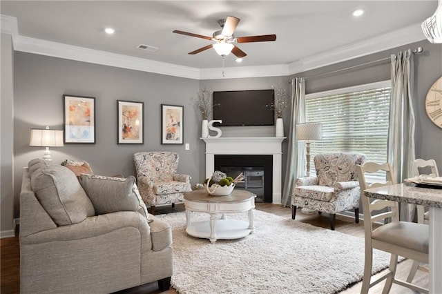 living room featuring ceiling fan, wood-type flooring, and crown molding