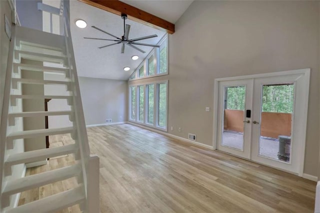 unfurnished living room featuring baseboards, high vaulted ceiling, a wealth of natural light, and french doors