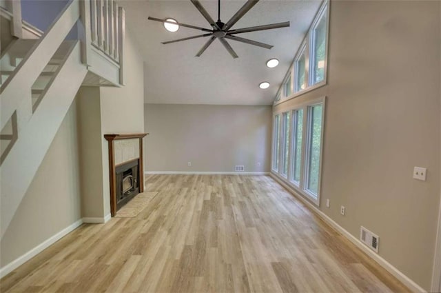 unfurnished living room with high vaulted ceiling, a healthy amount of sunlight, a fireplace, and light wood finished floors