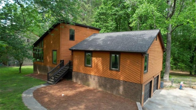 view of front facade featuring a shingled roof, a garage, driveway, a front lawn, and stairs