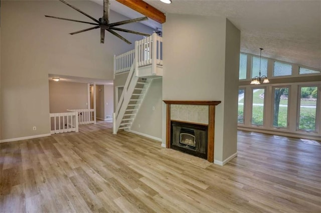 unfurnished living room with wood finished floors, high vaulted ceiling, and baseboards