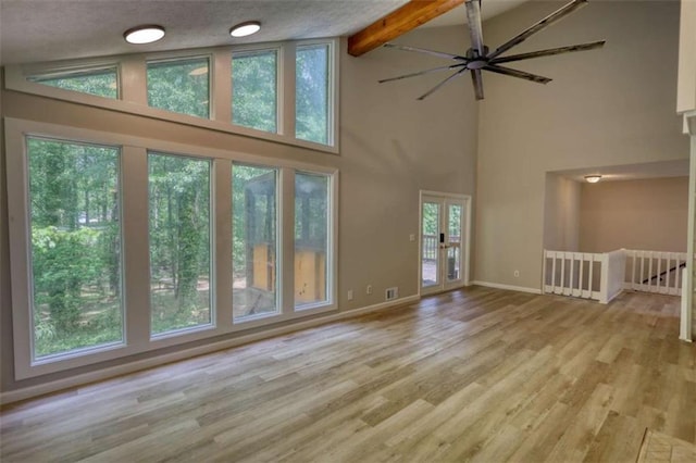 unfurnished living room featuring beamed ceiling, baseboards, wood finished floors, a ceiling fan, and high vaulted ceiling