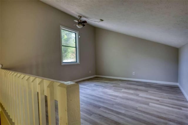 additional living space with a textured ceiling, wood finished floors, and baseboards