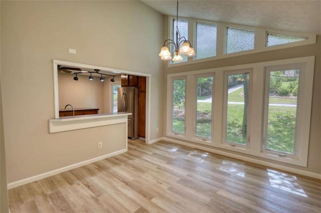 unfurnished dining area with baseboards, an inviting chandelier, light wood-style floors, and plenty of natural light