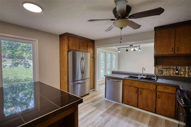 kitchen with a wealth of natural light, brown cabinets, appliances with stainless steel finishes, and a sink