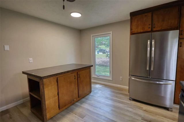kitchen with dark countertops, light wood finished floors, freestanding refrigerator, and baseboards