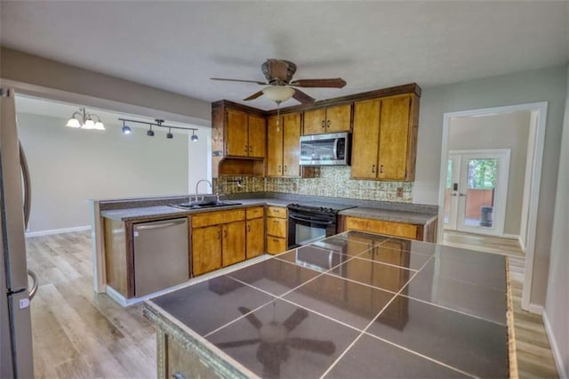 kitchen featuring stainless steel appliances, a ceiling fan, brown cabinets, and a sink