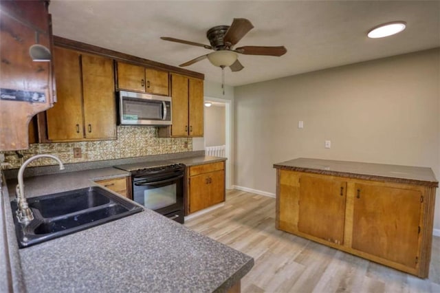 kitchen with stainless steel microwave, brown cabinets, ceiling fan, a sink, and black range with electric cooktop