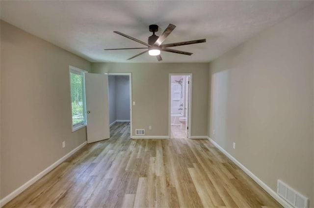 unfurnished room with visible vents, light wood-type flooring, a ceiling fan, and baseboards