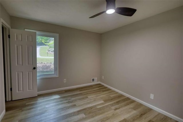 empty room with visible vents, a ceiling fan, light wood finished floors, and baseboards