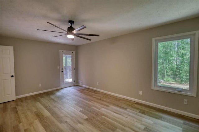 spare room featuring ceiling fan, light wood-style flooring, and baseboards