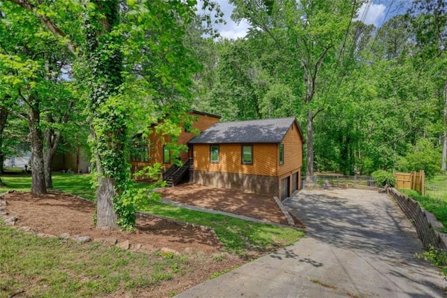 view of front of home featuring driveway, stairway, an attached garage, and fence