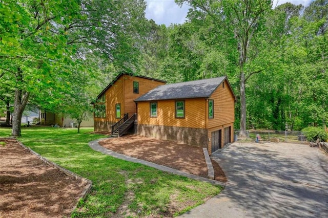 view of side of home featuring driveway, stairs, fence, a yard, and a garage