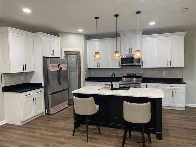 kitchen featuring decorative light fixtures, white cabinets, and appliances with stainless steel finishes